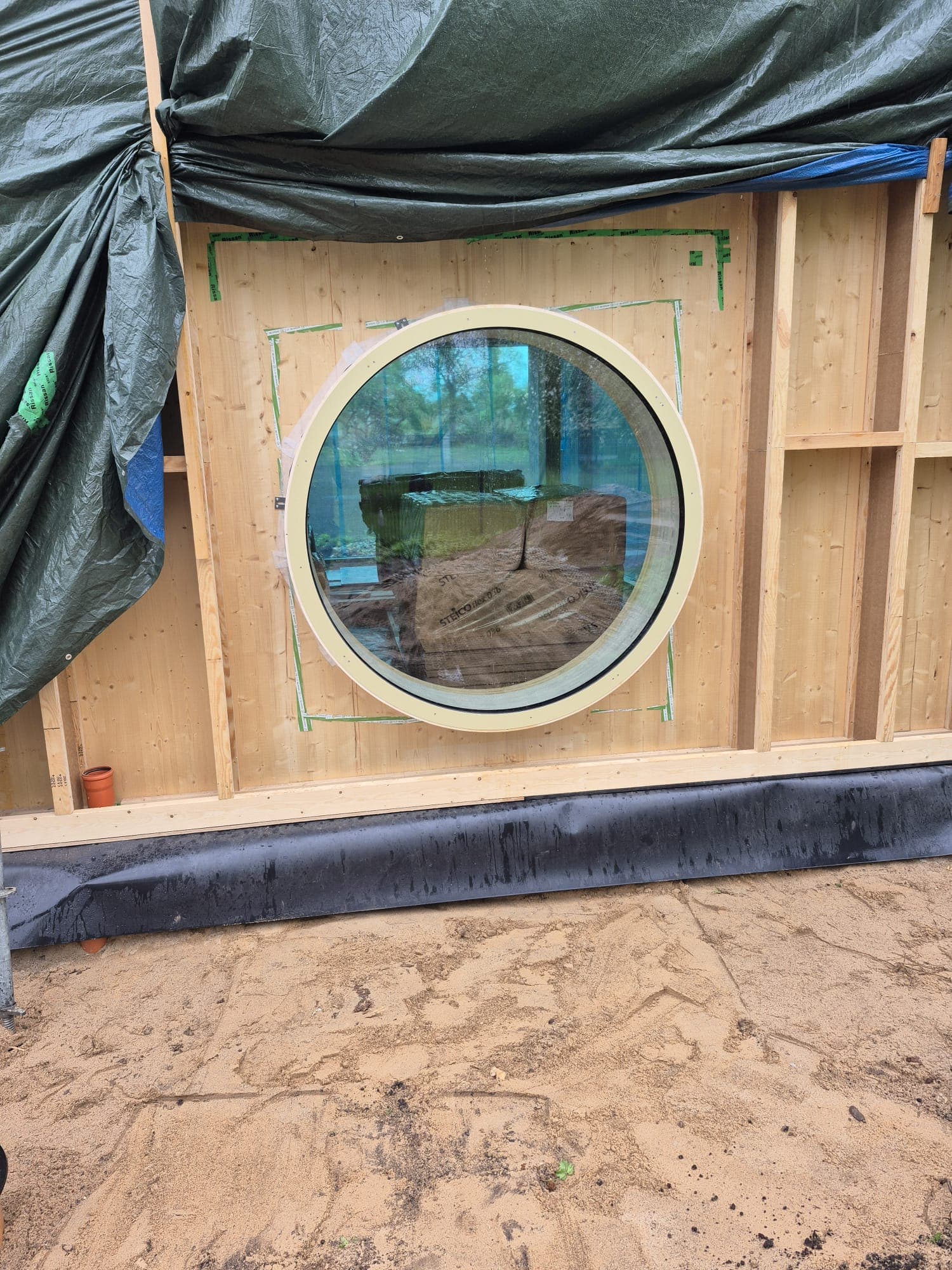 Round window installed in timber frame wall exterior during construction