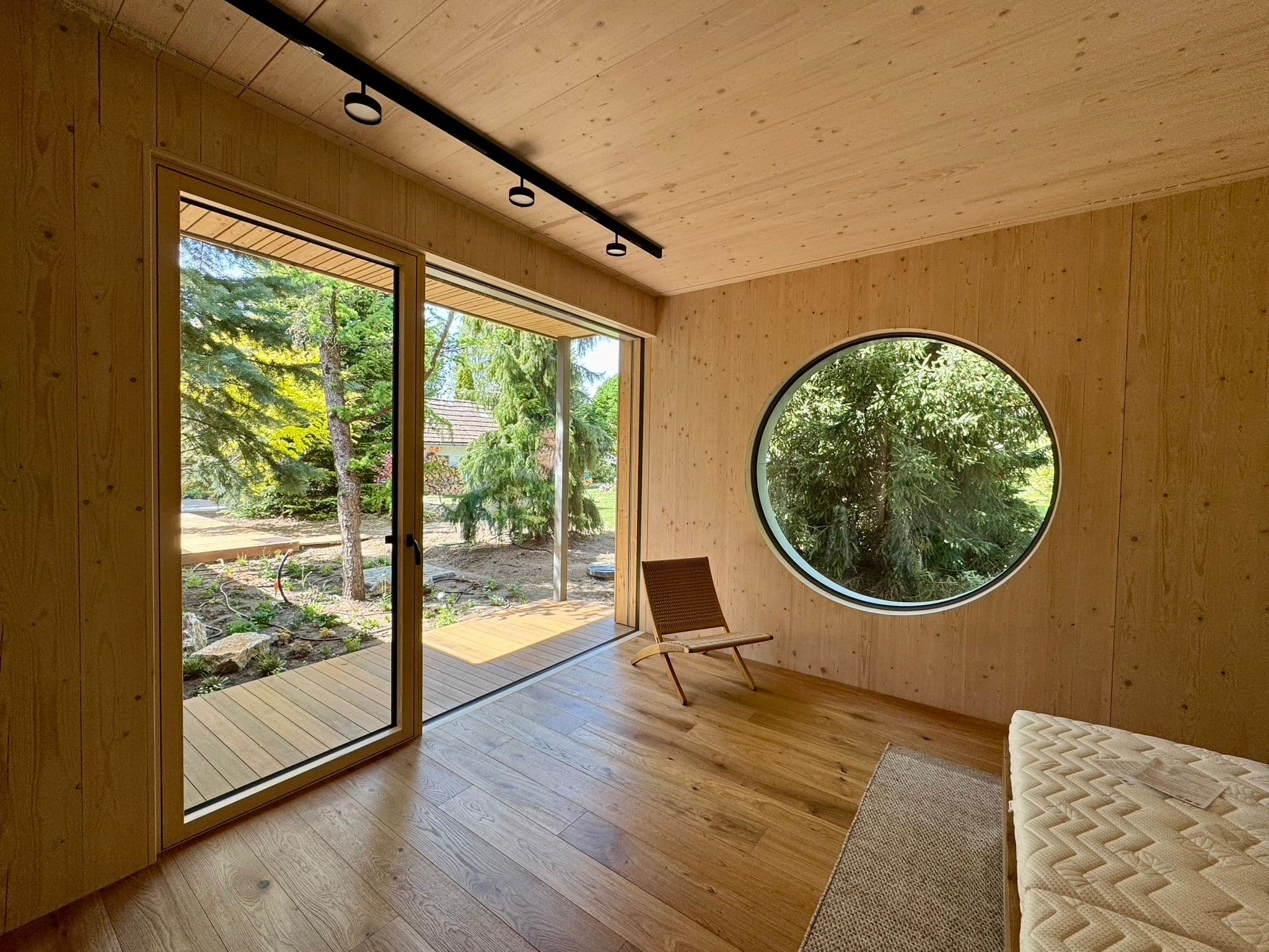 O360 round window in finished timber interior with garden view